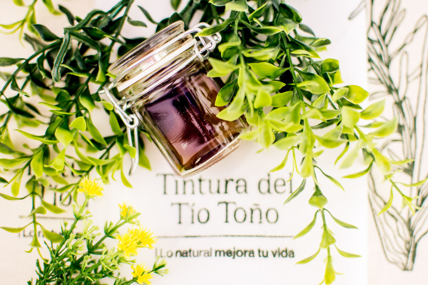 Tintura del Tío Toño en frasco de vidrio junto a lienzo bordado de la marca